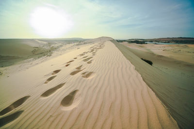 Scenic view of sand dunes at beach against sky