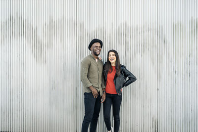 Laughing young couple standing against wall