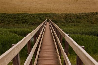 Footbridge amidst grassy field at dusk