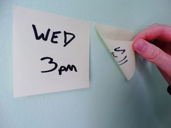 Cropped hand removing adhesive note on wall