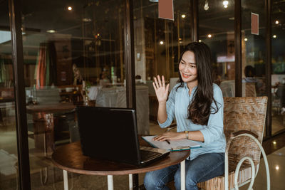 Young woman using laptop at cafe