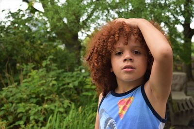 Portrait of cute boy standing against trees