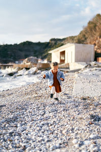 Full length of boy on shore against sky