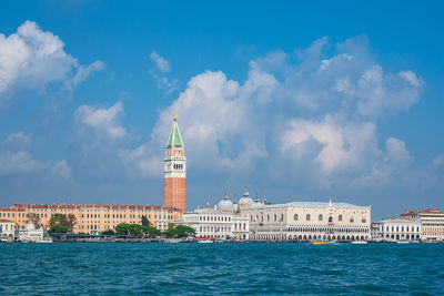 View of buildings by sea against cloudy sky