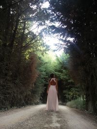 Rear view of women standing on road amidst trees