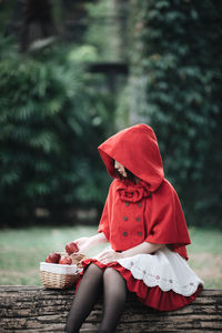 Midsection of woman sitting on bench against trees