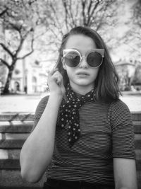 Portrait of woman wearing sunglasses standing against trees