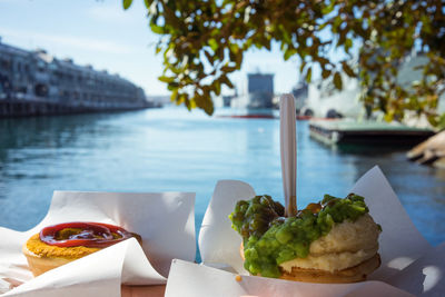 Close-up of fast food on table against lake