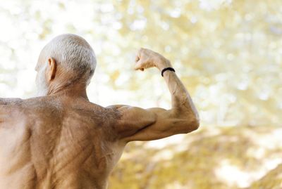 Rear view of shirtless man flexing muscles