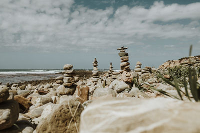 Stones stacked at beach against sky