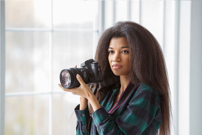 A beautiful african-american photographer girl with a camera. photo shoot in the studio.