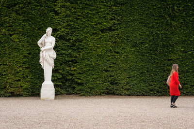 Side view of woman walking by hedge