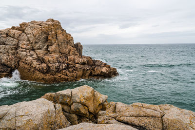 Rock formation on sea shore against sky