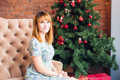 Portrait of smiling young woman with christmas tree