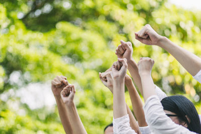 People with arms raised against trees