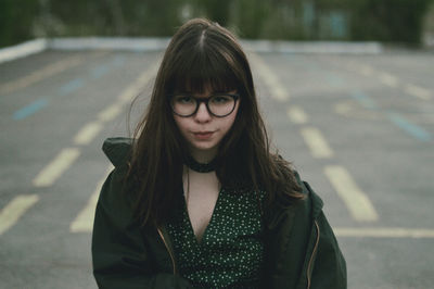 Portrait of a beautiful young woman standing on road in city