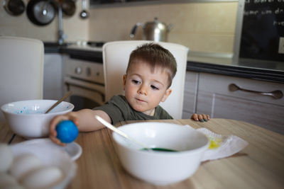 Close-up of cute baby boy holding bowl on table