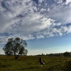 Rear view of person on field against sky