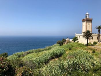 Scenic view of sea and buildings against clear blue sky