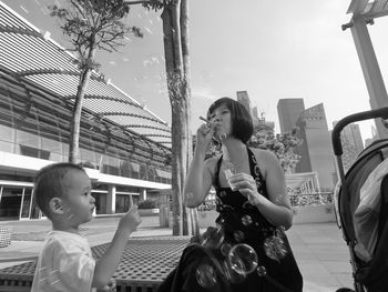 Mother and son playing with bubbles in city