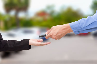 Cropped hand giving car key to female customer