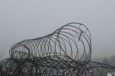 Low angle view of barbed wire against sky