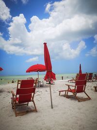 Deck chairs on beach against sky