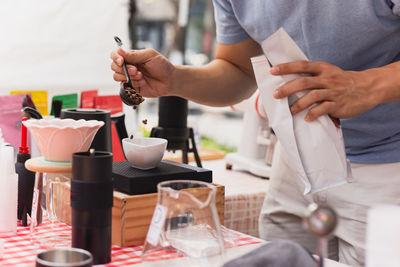 Barista weighing coffee grains on digital scale.