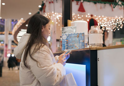 A young girl stands behind a counter in a shopping mall.