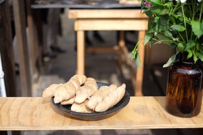 Breads served in plate on wooden table by flower vase