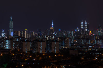 Illuminated buildings in city against sky at night