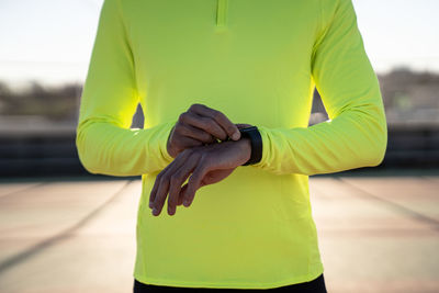 Male athlete checking time at sports court during sunny day