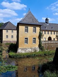 Buildings by river against sky