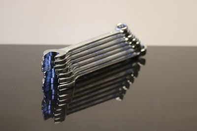 Close-up of silver metal spanners and wrenches on a reflective glossy surface 