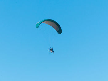 Low angle view of person paragliding against blue sky