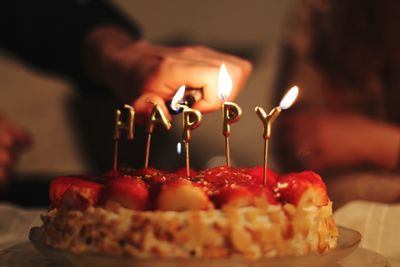 Cropped hand lighting birthday candles on cake