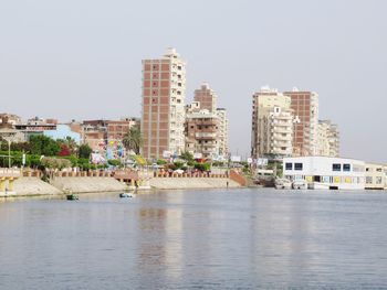 Buildings by sea against clear sky