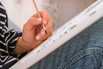 Painting on canvas by numbers and numbered jars of paint. woman draws with a brush painting