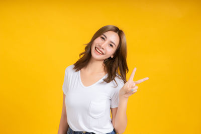 Young woman smiling against yellow background