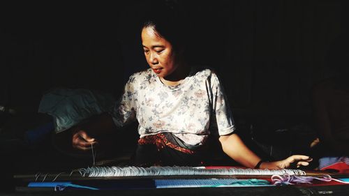 Young woman looking away while sitting on table