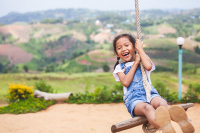 Full length of girl swinging at playground