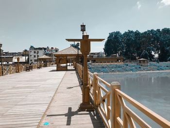 Footpath by pier amidst buildings against sky