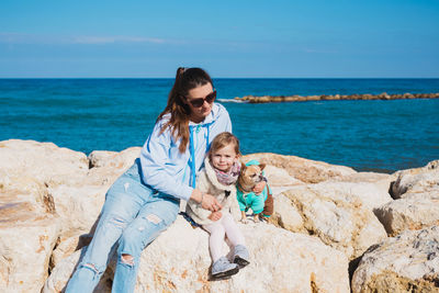 Portrait of woman sitting on rock at beach