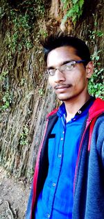 Portrait of young man standing against plants