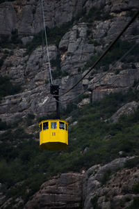 Low angle view of overhead cable car against mountains