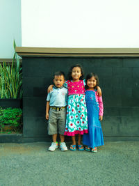 Portrait of smiling siblings standing against wall