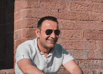 Portrait of man wearing sunglasses against wall