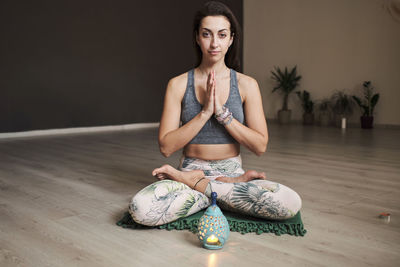 Young woman meditates alone in yoga studio with aroma lamp