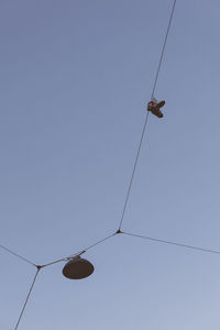 Low angle view of shoes hanging on rope cable clear sky