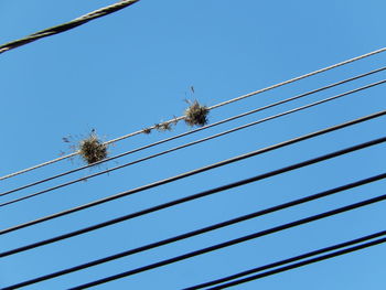 Low angle view of electricity pylon against blue sky